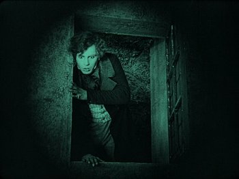 Movie still from “Nosferatu” (1922), directed by F.W. Murnau – A man standing inside of a building at night; Medium shot, High angle