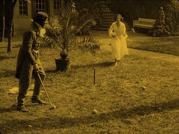 Movie still from “Nosferatu” (1922), directed by F.W. Murnau – A man and a woman playing a game of croquet in a yard; Wide shot, High angle