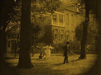 Movie still from “Nosferatu” (1922), directed by F.W. Murnau – A man and a woman playing croquet in a yard; Extreme Wide shot, High angle