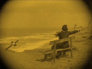 Movie still from “Nosferatu” (1922), directed by F.W. Murnau – A person sitting on a bench on the beach; Extreme Wide shot, High angle