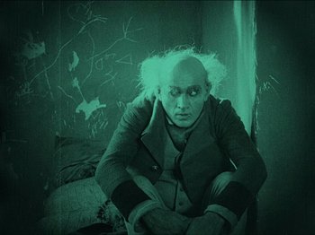 Movie still from “Nosferatu” (1922), directed by F.W. Murnau – An old man sitting on a bed in front of a tree; Medium shot, High angle