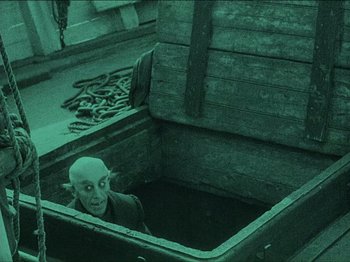 Movie still from “Nosferatu” (1922), directed by F.W. Murnau – A man with a bald head is in a wooden box; Wide shot, High angle