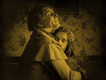 Movie still from “Nosferatu” (1922), directed by F.W. Murnau – An older woman hugging a younger woman in a room; Medium shot, High angle
