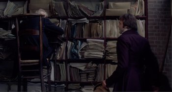 Movie still from “Nosferatu the Vampyre” (1979), directed by Werner Herzog – A man and a woman standing in front of a book case; Medium shot, Over the shoulder angle