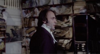 Movie still from “Nosferatu the Vampyre” (1979), directed by Werner Herzog – A man standing in front of a wall of papers; Medium shot, Over the shoulder angle