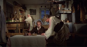 Movie still from “Nosferatu the Vampyre” (1979), directed by Werner Herzog – A man sitting at a table with a bowl of food; Wide shot, High angle