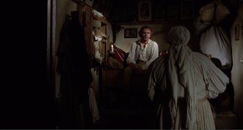 Movie still from “Nosferatu the Vampyre” (1979), directed by Werner Herzog – A man sitting on a chair in a dark room; Wide shot, Over the shoulder angle