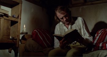Movie still from “Nosferatu the Vampyre” (1979), directed by Werner Herzog – A man sitting on a bed reading a book; Medium shot, Low angle