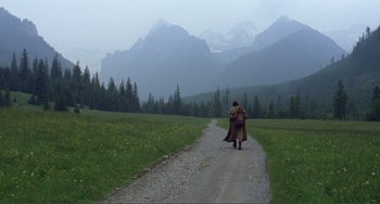 Movie still from “Nosferatu the Vampyre” (1979), directed by Werner Herzog – A man in a long coat walking down a dirt road in the mountains; Extreme Wide shot, High angle