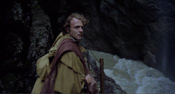 Movie still from “Nosferatu the Vampyre” (1979), directed by Werner Herzog – A man with a sword standing next to a body of water; Medium shot, High angle