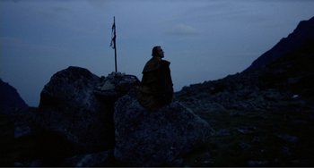 Movie still from “Nosferatu the Vampyre” (1979), directed by Werner Herzog – A man sitting on top of a large rock in the dark; Wide shot, Low angle