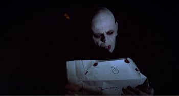 Movie still from “Nosferatu the Vampyre” (1979), directed by Werner Herzog – An evil looking man holding an open bag of food; Close Up shot, Over the shoulder angle