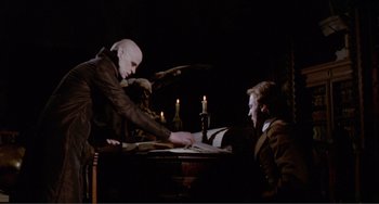 Movie still from “Nosferatu the Vampyre” (1979), directed by Werner Herzog – Two men sitting at a table with a book and candles; Medium shot, High angle