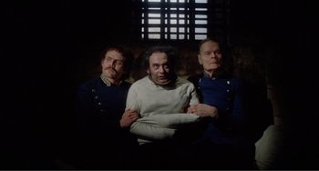 Movie still from “Nosferatu the Vampyre” (1979), directed by Werner Herzog – A group of men standing next to each other in front of a window; Medium shot, High angle