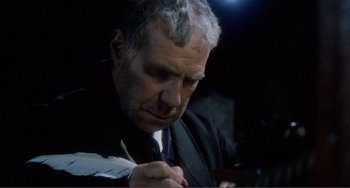 Movie still from “Nosferatu the Vampyre” (1979), directed by Werner Herzog – An older man in a black suit writing on a piece of paper; Close Up shot, High angle