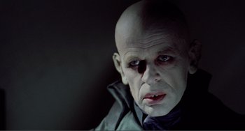 Movie still from “Nosferatu the Vampyre” (1979), directed by Werner Herzog – A man with bald head wearing a black shirt; Close Up shot, Low angle