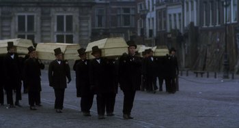 Movie still from “Nosferatu the Vampyre” (1979), directed by Werner Herzog – A group of men walking down a street holding umbrellas; Wide shot, High angle