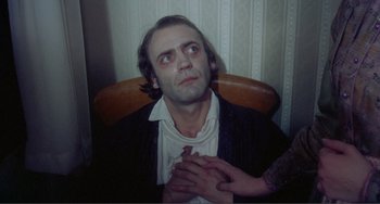 Movie still from “Nosferatu the Vampyre” (1979), directed by Werner Herzog – A man sitting in front of a woman with his hands clasped together; Close Up shot, High angle