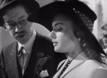 Movie still from “Notorious” (1946), directed by Alfred Hitchcock – A man and a woman wearing hats and suits; Close Up shot, Over the shoulder angle