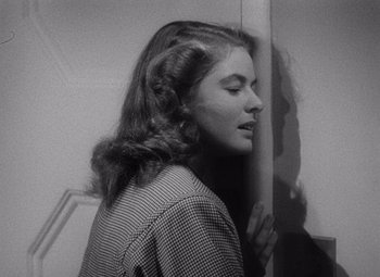 Movie still from “Notorious” (1946), directed by Alfred Hitchcock – A black - and - white photo of a woman leaning against a wall; Close Up shot, Low angle