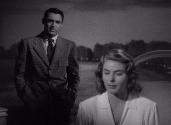Movie still from “Notorious” (1946), directed by Alfred Hitchcock – A man and a woman standing next to each other in front of trees; Medium shot, Over the shoulder angle