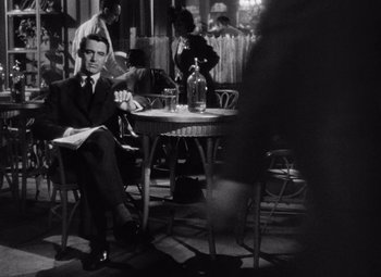 Movie still from “Notorious” (1946), directed by Alfred Hitchcock – A black and white photo of a man sitting at a table; Medium shot, Low angle