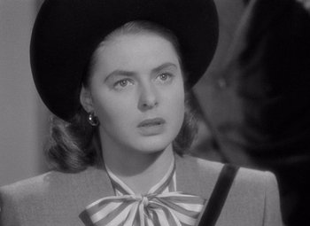 Movie still from “Notorious” (1946), directed by Alfred Hitchcock – A black and white photo of a woman in a hat and a bow tie; Close Up shot, Over the shoulder angle