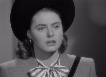 Movie still from “Notorious” (1946), directed by Alfred Hitchcock – A black and white photo of a woman in a hat and bow tie; Close Up shot, Over the shoulder angle