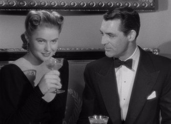 Movie still from “Notorious” (1946), directed by Alfred Hitchcock – A man and a woman sitting next to each other at a table; Medium shot, Over the shoulder angle