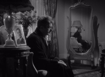 Movie still from “Notorious” (1946), directed by Alfred Hitchcock – A man sitting in front of a mirror in a room; Medium shot, Over the shoulder angle