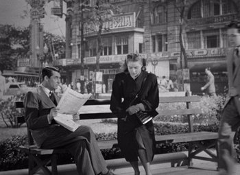 Movie still from “Notorious” (1946), directed by Alfred Hitchcock – A man and a woman are sitting on a bench; Wide shot, High angle