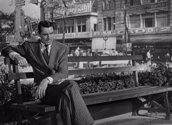 Movie still from “Notorious” (1946), directed by Alfred Hitchcock – A black and white photo of a man sitting on a park bench; Medium shot, Over the shoulder angle