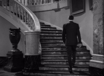 Movie still from “Notorious” (1946), directed by Alfred Hitchcock – A man in a suit walking down a set of stairs; Wide shot, High angle