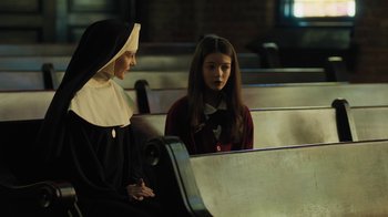 Movie still from “Novitiate” (2017), directed by Maggie Betts – A nun sitting next to a young girl in a church; Medium shot, High angle