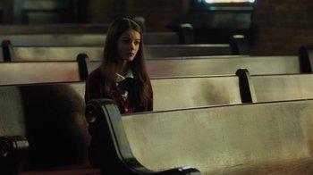 Movie still from “Novitiate” (2017), directed by Maggie Betts – A girl sitting alone in a pew looking sad; Medium shot, High angle