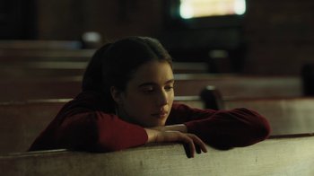 Movie still from “Novitiate” (2017), directed by Maggie Betts – A woman sitting on a bench in a dark room; Close Up shot, High angle