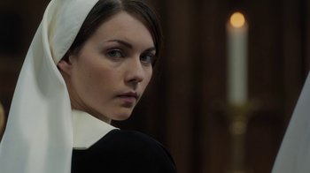 Movie still from “Novitiate” (2017), directed by Maggie Betts – A woman wearing a nun's outfit with a white head scarf; Close Up shot, Over the shoulder angle