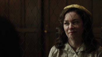Movie still from “Novitiate” (2017), directed by Maggie Betts – A woman wearing a yellow hat and looking at the camera through a chain link fence; Close Up shot, Over the shoulder angle
