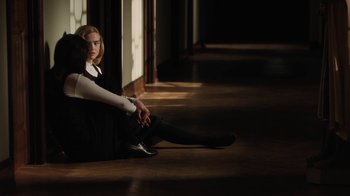 Movie still from “Novitiate” (2017), directed by Maggie Betts – A woman sitting on the ground in a dark room; Medium shot, High angle