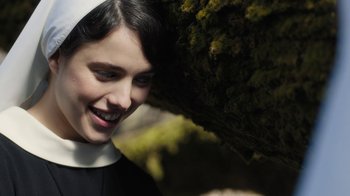 Movie still from “Novitiate” (2017), directed by Maggie Betts – A woman wearing a nun's outfit standing next to a tree; Close Up shot, Overhead angle