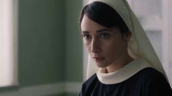 Movie still from “Novitiate” (2017), directed by Maggie Betts – A woman in a black dress and a white head scarf; Close Up shot, Over the shoulder angle