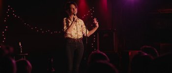 Movie still from “Obvious Child” (2014), directed by Gillian Robespierre – A woman standing on a stage holding a microphone; Medium shot, Over the shoulder angle
