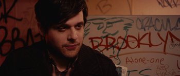 Movie still from “Obvious Child” (2014), directed by Gillian Robespierre – A person sitting in front of a wall; Close Up shot, Over the shoulder angle