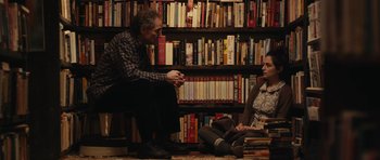 Movie still from “Obvious Child” (2014), directed by Gillian Robespierre – A man and a woman sitting in front of a book shelf; Medium shot, High angle
