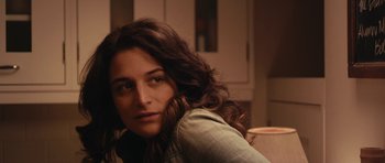 Movie still from “Obvious Child” (2014), directed by Gillian Robespierre – A woman with long brown hair sitting in a room; Close Up shot, Over the shoulder angle
