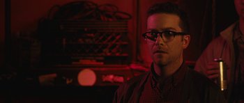Movie still from “Obvious Child” (2014), directed by Gillian Robespierre – A man with glasses is standing in front of a radio; Close Up shot, Over the shoulder angle