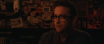 Movie still from “Obvious Child” (2014), directed by Gillian Robespierre – A man with glasses is sitting in front of a wall; Close Up shot, Over the shoulder angle