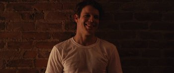 Movie still from “Obvious Child” (2014), directed by Gillian Robespierre – A man smiling for the camera in front of a brick wall; Close Up shot, Low angle