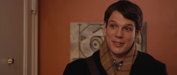 Movie still from “Obvious Child” (2014), directed by Gillian Robespierre – A man wearing a scarf standing in front of a painting; Close Up shot, Over the shoulder angle