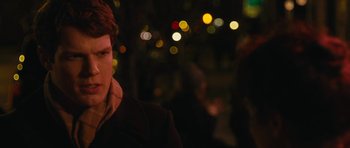 Movie still from “Obvious Child” (2014), directed by Gillian Robespierre – A man in a black jacket standing in front of some lights at night; Close Up shot, Over the shoulder angle